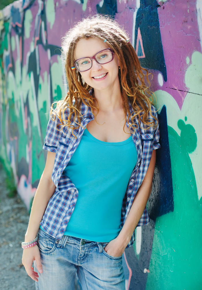 Girl with dreadlocks against a wall with graffiti